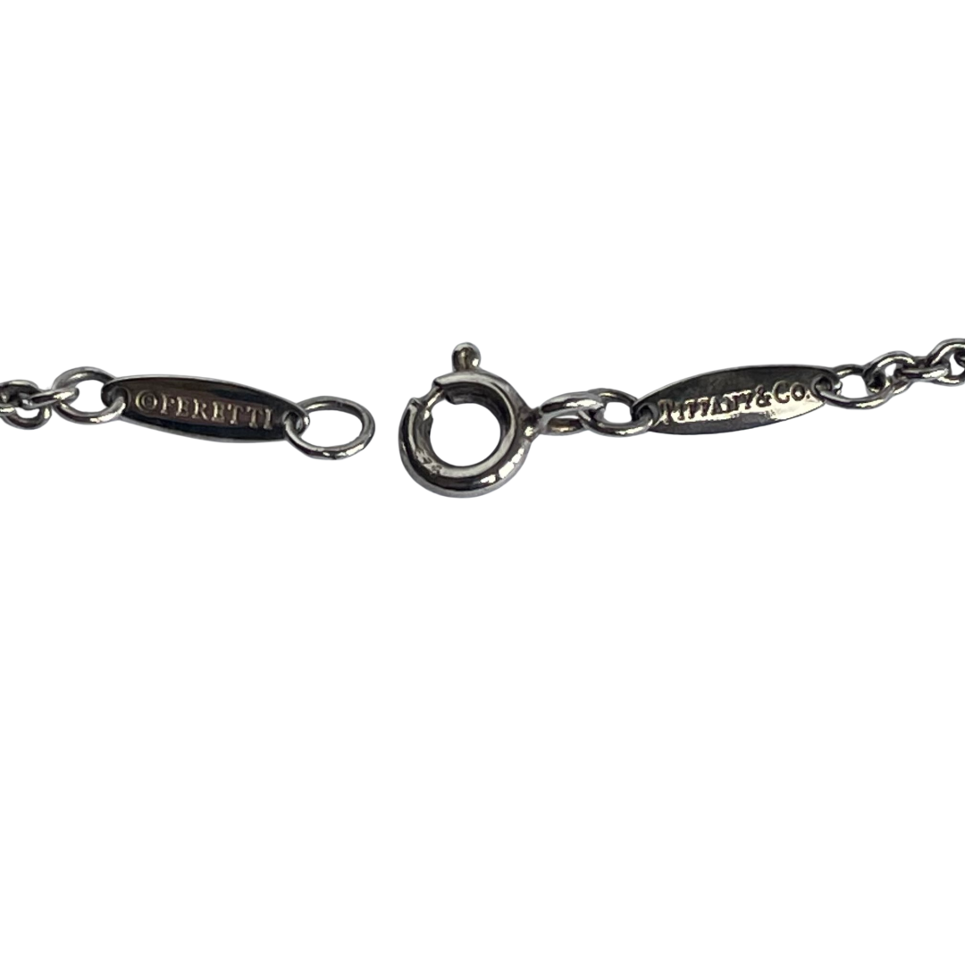 Vintage Tiffany & Co. Elsa Peretti Open Heart sterling silver lariat necklace featuring a sliding open heart pendant and a cultured freshwater pearl on a 19-inch chain, shown in polished pre-owned condition with Tiffany box and pouch.