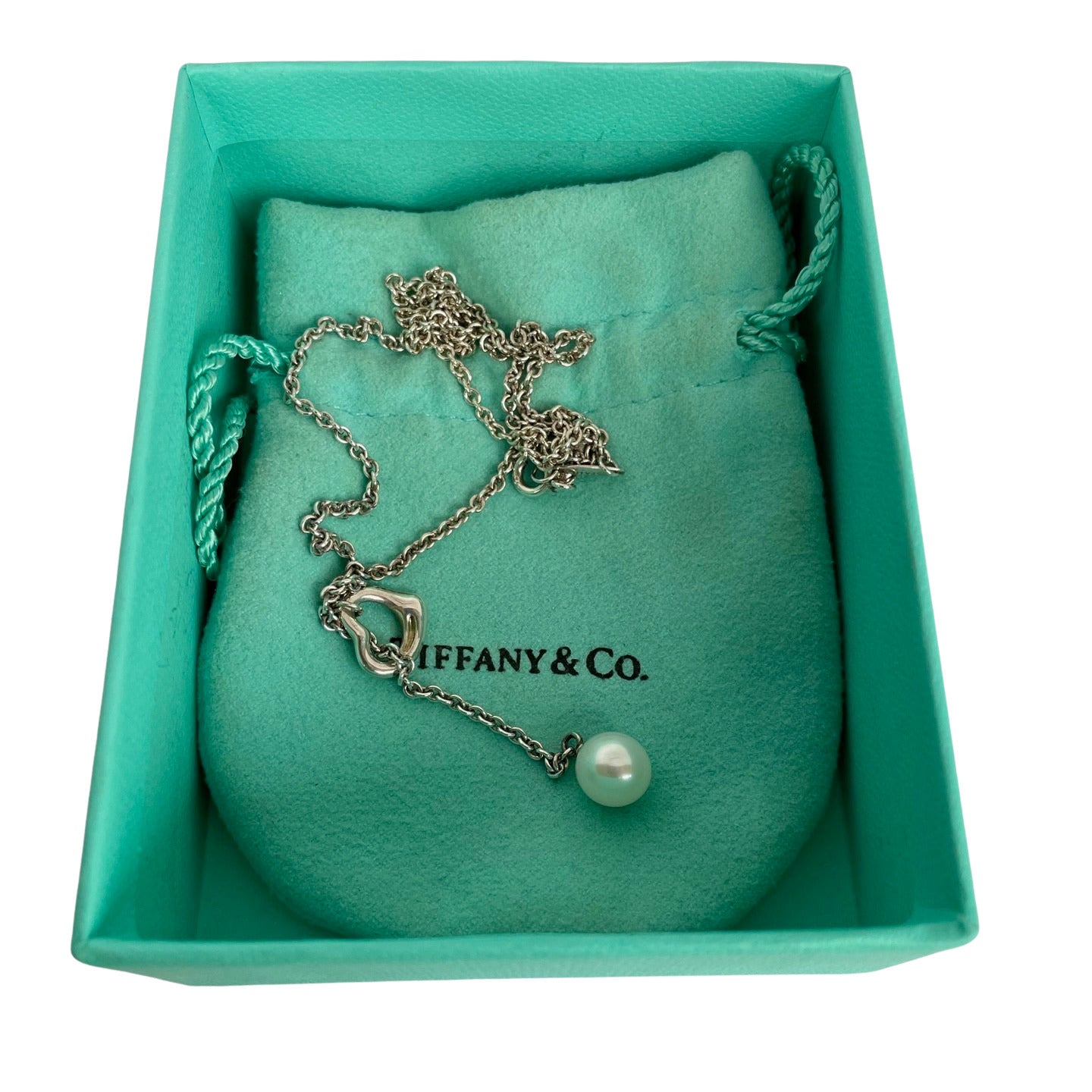 Vintage Tiffany & Co. Elsa Peretti Open Heart sterling silver lariat necklace featuring a sliding open heart pendant and a cultured freshwater pearl on a 19-inch chain, shown in polished pre-owned condition with Tiffany box and pouch.