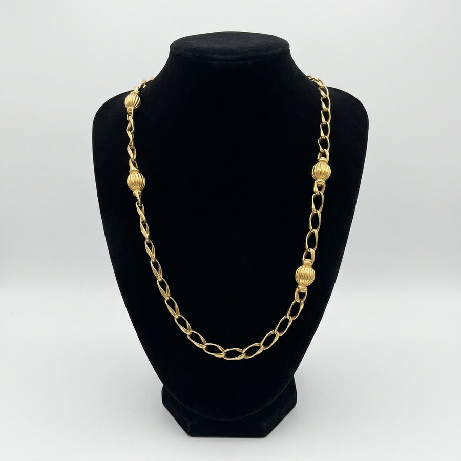 1980s vintage Christian Dior long gold-plated necklace featuring open oval links punctuated by four ribbed gold ball stations   displayed on black bust.