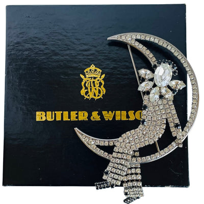 Large vintage 1980s Butler and Wilson crystal Harlequin Pierrot on moon brooch displayed on its black and gold crested gift box.
