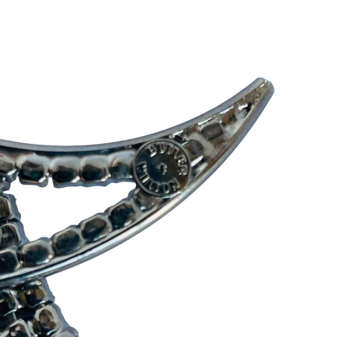 close up of Butler & Wilson maker's mark on large vintage 1980s Butler and Wilson crystal Harlequin Pierrot on moon brooch on white background.