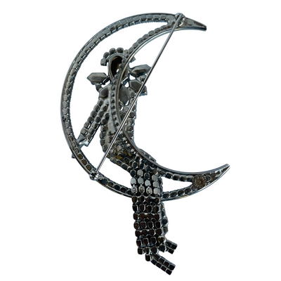 reverse of large vintage 1980s Butler and Wilson crystal Harlequin Pierrot on moon brooch on white background.
