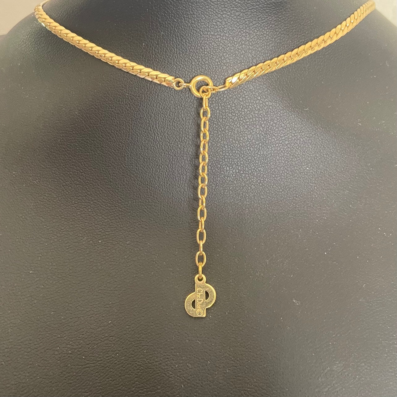 Close-up of the reverse side of a vintage Christian Dior necklace charm, showing the official Chr.Dior copyright signature hallmark stamp.