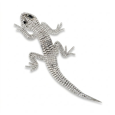 A magnificent 19 cm vintage Butler & Wilson silver-tone articulated lizard brooch encrusted with clear crystals and black eyes, on a white background.