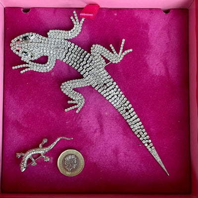 A magnificent 19 cm vintage Butler & Wilson silver-tone articulated lizard brooch encrusted with clear crystals and black eyes, shown in its Butler & Wilson pink box with a small lizard and £1 coin for scale