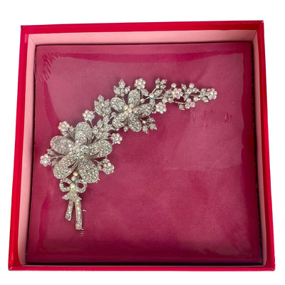 A large silver-tone Butler & Wilson floral corsage brooch on a white background, featuring trailing flowers and a sparkling bow detailed with clear and iridescent Aurora Borealis crystals still sealed in original pink Butler & Wilson box,