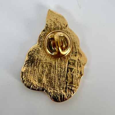 The back of a vintage YSL gold brooch showing a push-on stud closure and an engraved stamp reading Made in France with the vertical YSL logo.