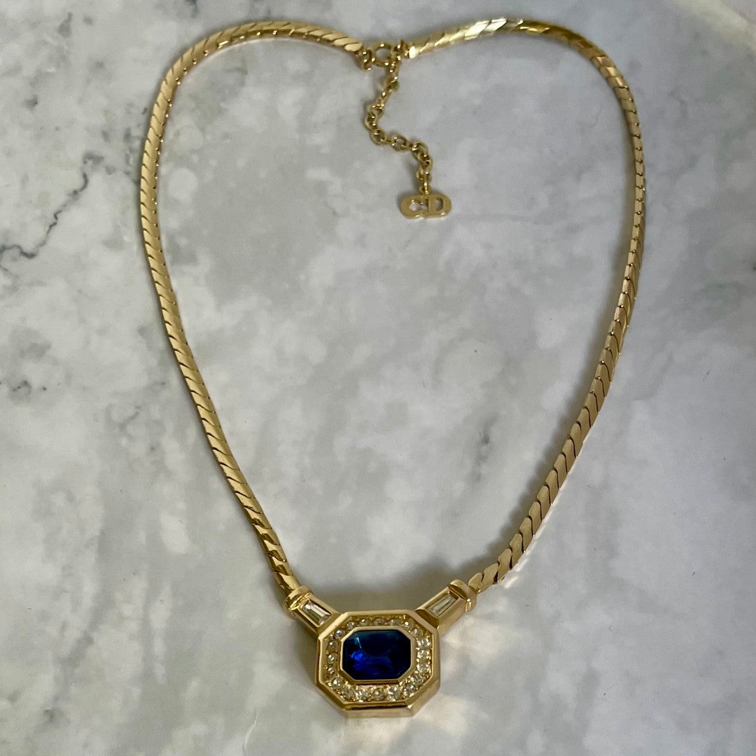 A vintage 1980s Christian Dior gold-plated demi-parure set featuring a flat herringbone chain necklace with a central octagonal pendant displayed on marble