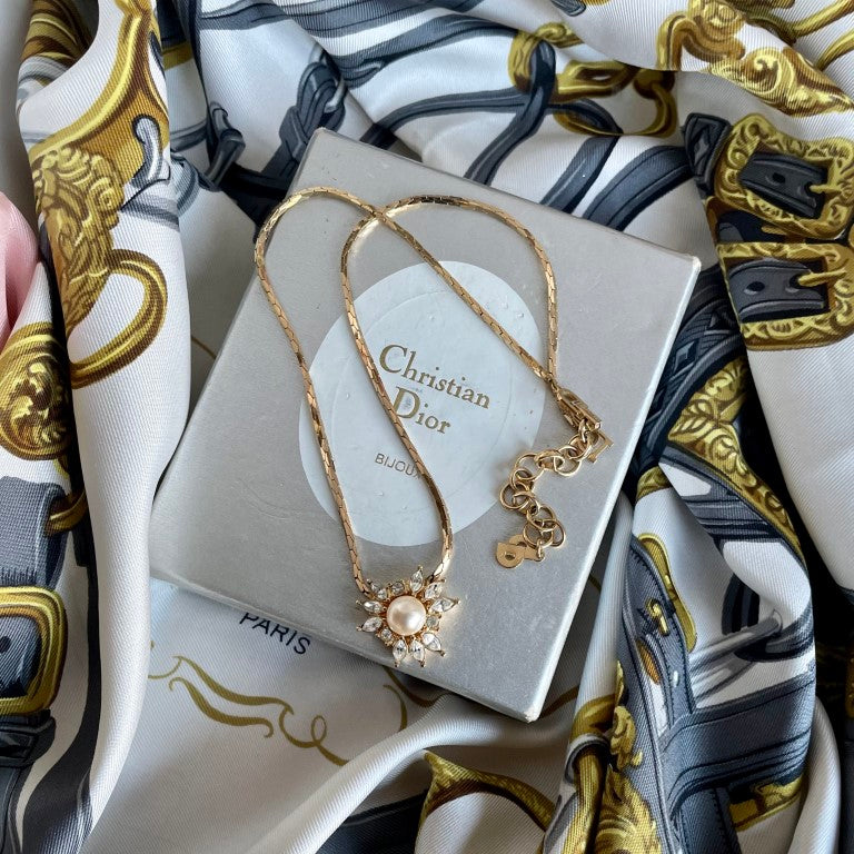 vintage Christian Dior sunburst pendant with central faux mabé pearl and alternating round and marquise crystals styled on Christian Dior box and Hermes scarf